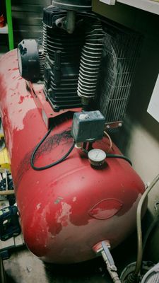 a red air compressor sitting on top of a red tank