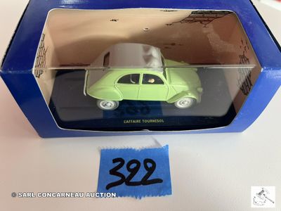 une petite voiture verte dans une boîte bleue avec une étiquette de prix