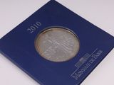 un gros plan d'une pièce de monnaie dans une boîte bleue posée sur une surface blanche