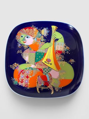 une image représentant une assiette décorative sur laquelle figure une femme jouant d'un instrument de musique