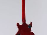 a red guitar hanging from a white wall with a white background