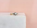 an engagement ring with two diamonds on top of a white marble block