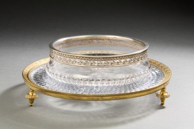 a silver and gold plate with a glass bowl on top of it
