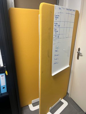 un tableau blanc accroché au mur, à côté d'une cloison jaune