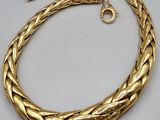 a gold plated necklace with a braid design on a white background
