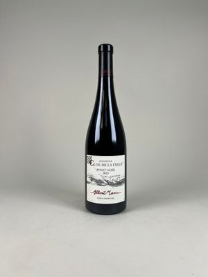 une bouteille de vin rouge posée sur une table blanche