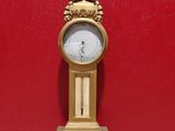 une horloge dorée posée sur une table devant un mur rouge
