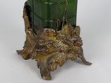 a green vase with a bird on it on a table
