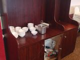 a small wooden cabinet with bowls and cups on it
