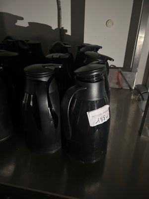 bottles of coffee sit on a metal shelf in a kitchen