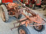 un tracteur rouillé dans un garage, à côté d'autres tracteurs