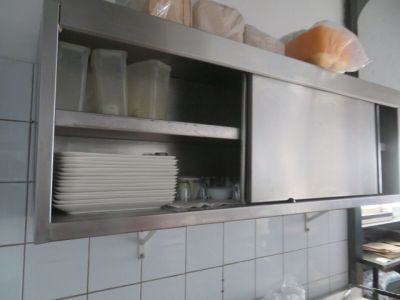 une cuisine équipée d'une étagère en inox et de beaucoup de vaisselle