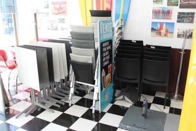 sol à carreaux noirs et blancs dans un salon de coiffure pour hommes, avec des fauteuils et des planches de surf