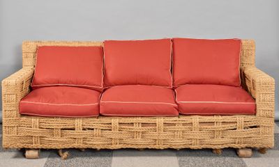 une photo d'un canapé en osier avec des coussins rouges