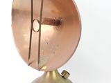 a small copper object on a stand on a white surface