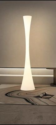 un lampadaire blanc posé sur un tapis dans une pièce
