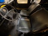 a black and yellow bus with a steering wheel and dashboard