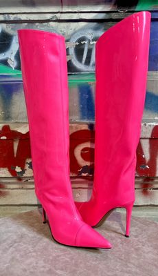 pair of pink high heeled boots sitting on the ground in front of a graffiti covered wall