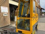 un chariot élévateur jaune garé devant un immeuble