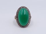 a close up of a ring with a green stone surrounded by diamonds