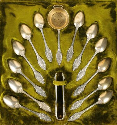 des cuillères et des couteaux-cuillères en argent dans une boîte verte, avec une cuillère au milieu