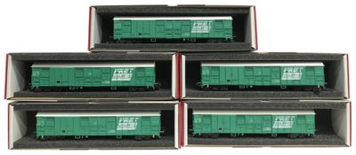 quatre wagons verts dans des boîtes, posés sur une surface blanche