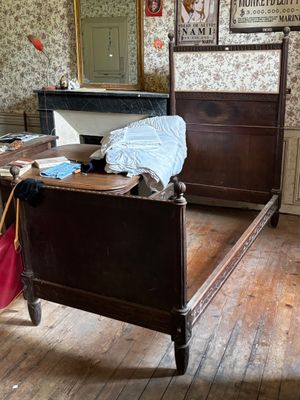 une chambre avec un lit, une commode, un miroir et une valise