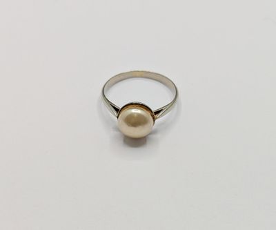 a pearl ring on a white surface