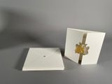 two white cards with gold foil flowers on them sitting on a table