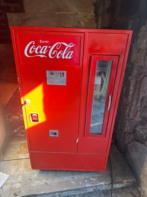 a red coca cola machine sitting on the side of a building