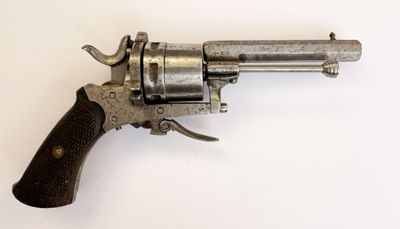 un vieux revolver avec une poignée en bois sur une surface blanche