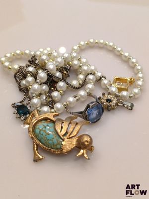 une photo d'un collier orné d'un oiseau et de perles