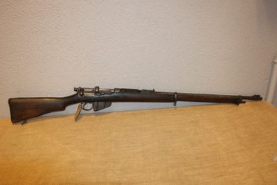 Un vieux fusil est posé sur une table près d'un mur.