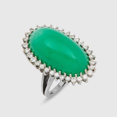 gros plan d'une bague avec une pierre verte entourée de diamants
