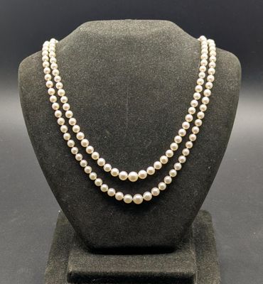 un collier de perles blanches sur un mannequin avec un fermoir en or