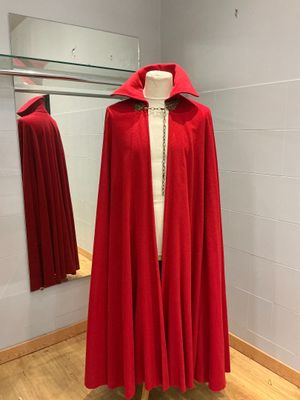 une cape rouge posée sur un pied de mannequin dans une pièce