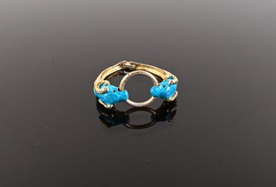 an image of a gold ring with blue stones on a black surface
