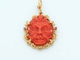 an image of a red and gold pendant with a face in the center