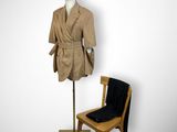 a mannequin sitting next to a chair and a coat on a stand