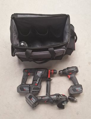 un sac noir contenant des outils, posé par terre