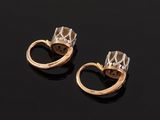 a pair of gold and diamond earrings on a black surface