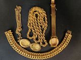 un gros plan sur un collier, un bracelet et une montre en or posés sur une surface noire