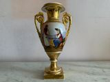 a gold vase with a painting on it sitting on a table