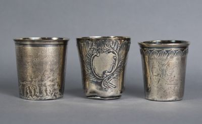 three silver shot glasses sitting next to each other on top of a table