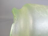 un vase en verre muni d'une anse verte, posé sur une table