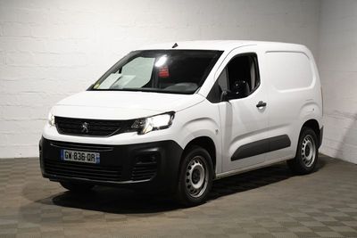 La camionnette blanche est garée dans une pièce blanche au sol à carreaux.