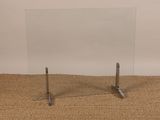 une photo d'une table en verre avec deux pieds en métal posée sur un tapis