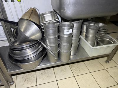 pots and pans are stacked on a metal shelf in a kitchen