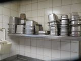 many pots and pans stacked on a shelf in a kitchen