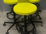Des chaises et des tabourets jaunes sont alignés contre un mur